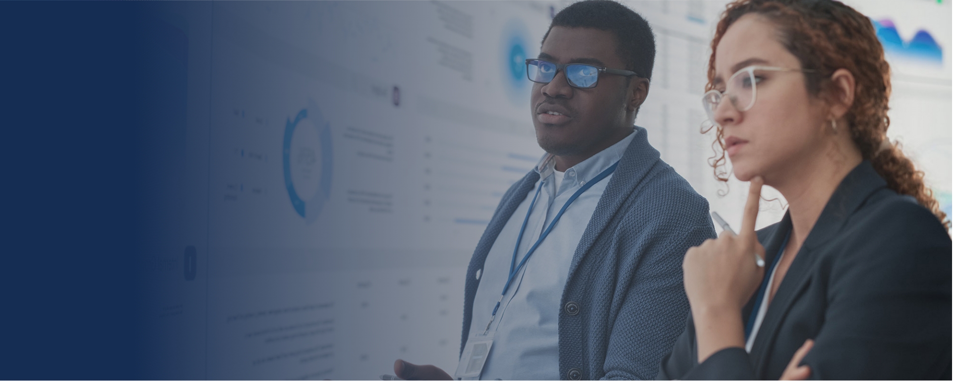 Two students standing in front of a computer screen showing data