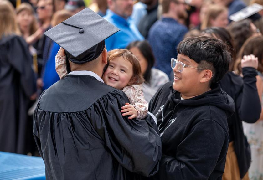 Children hug a graduate wearing a cap and gown