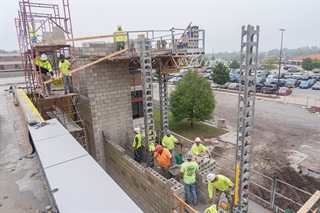 Construction workers working on erecting a second floor for Building Q
