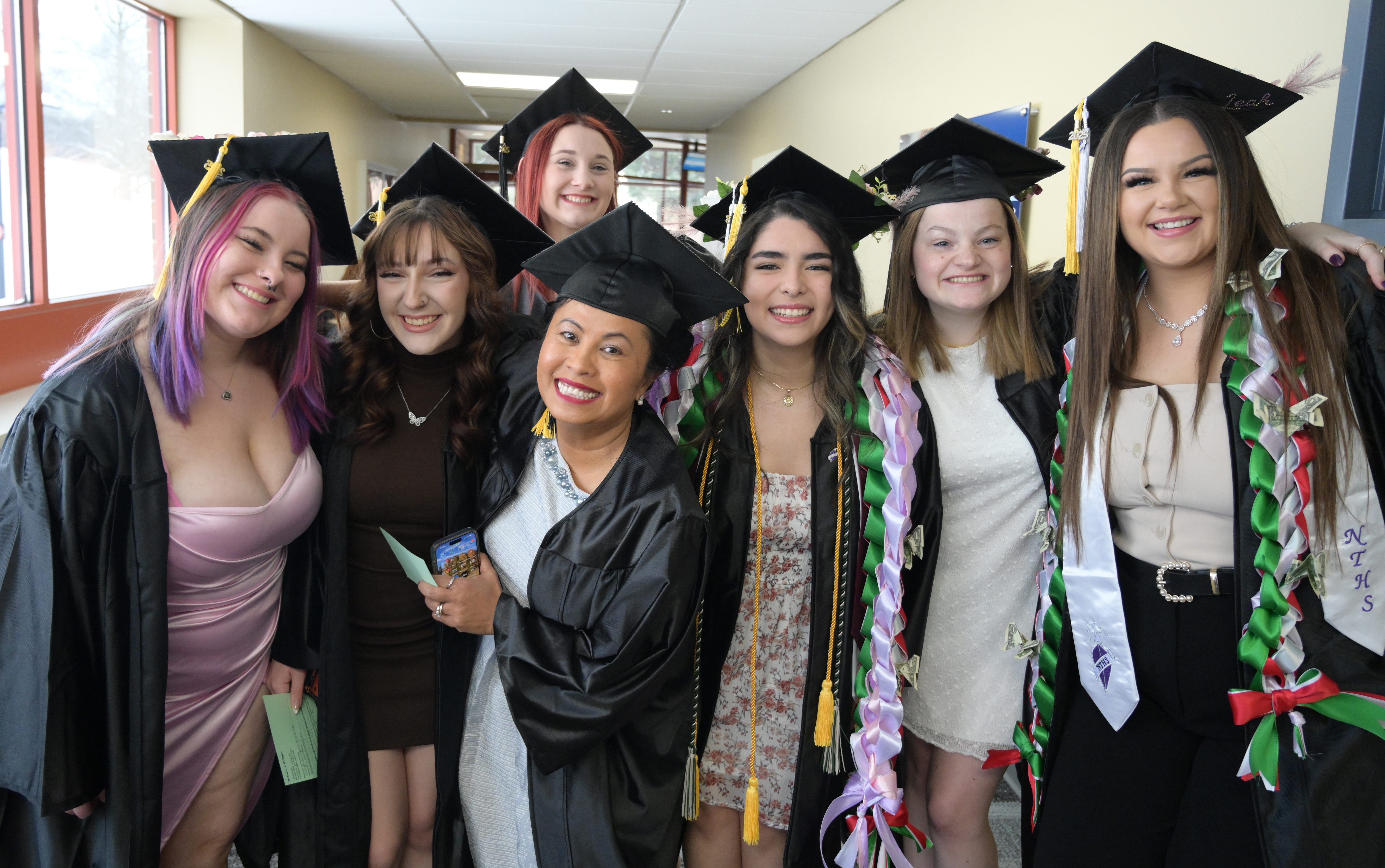 Group of female graduates celebrate wearing their robes and decorated mortarboard hats