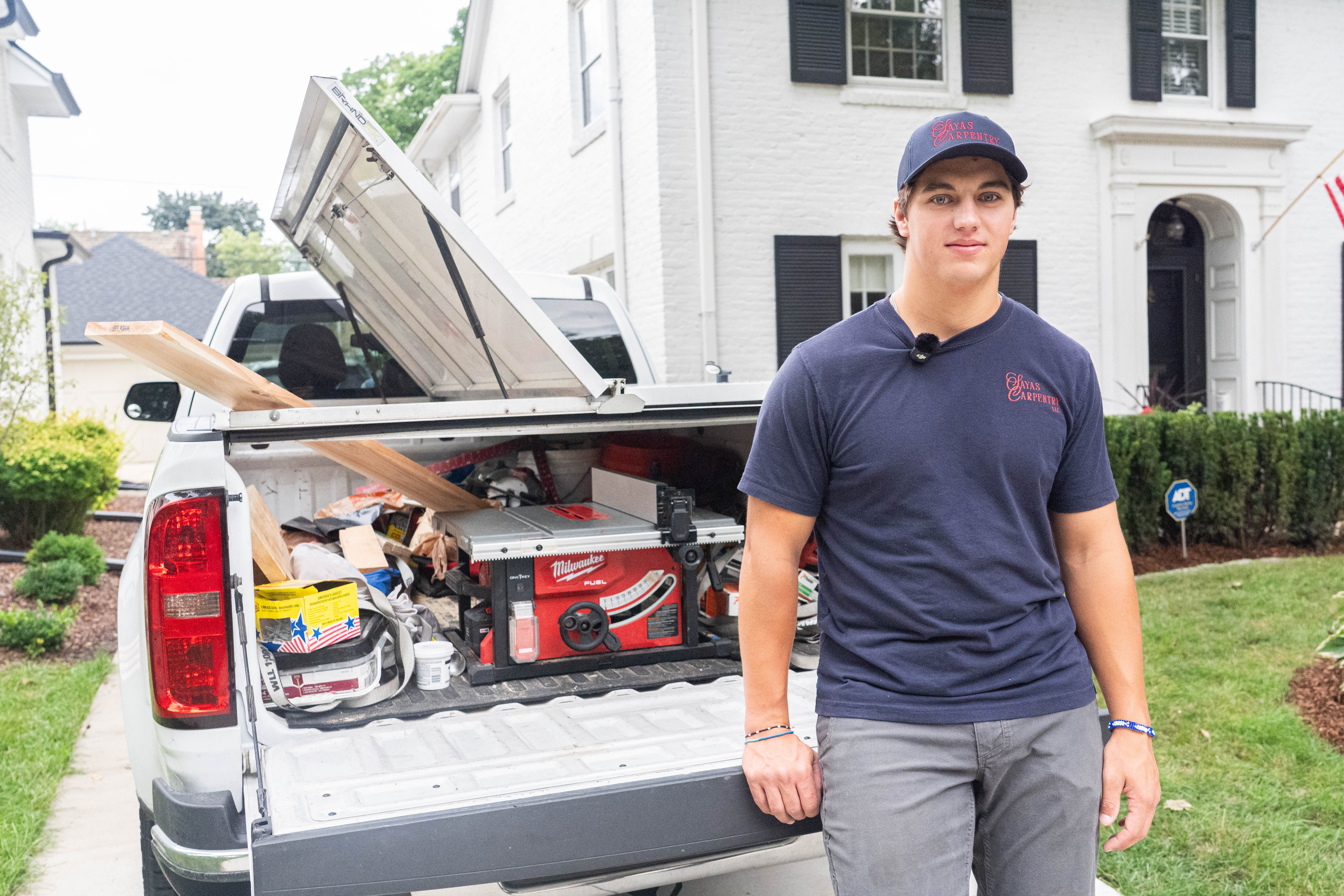 David Sayas leans against the tailgate of his truck. The truck bed is full of tools.