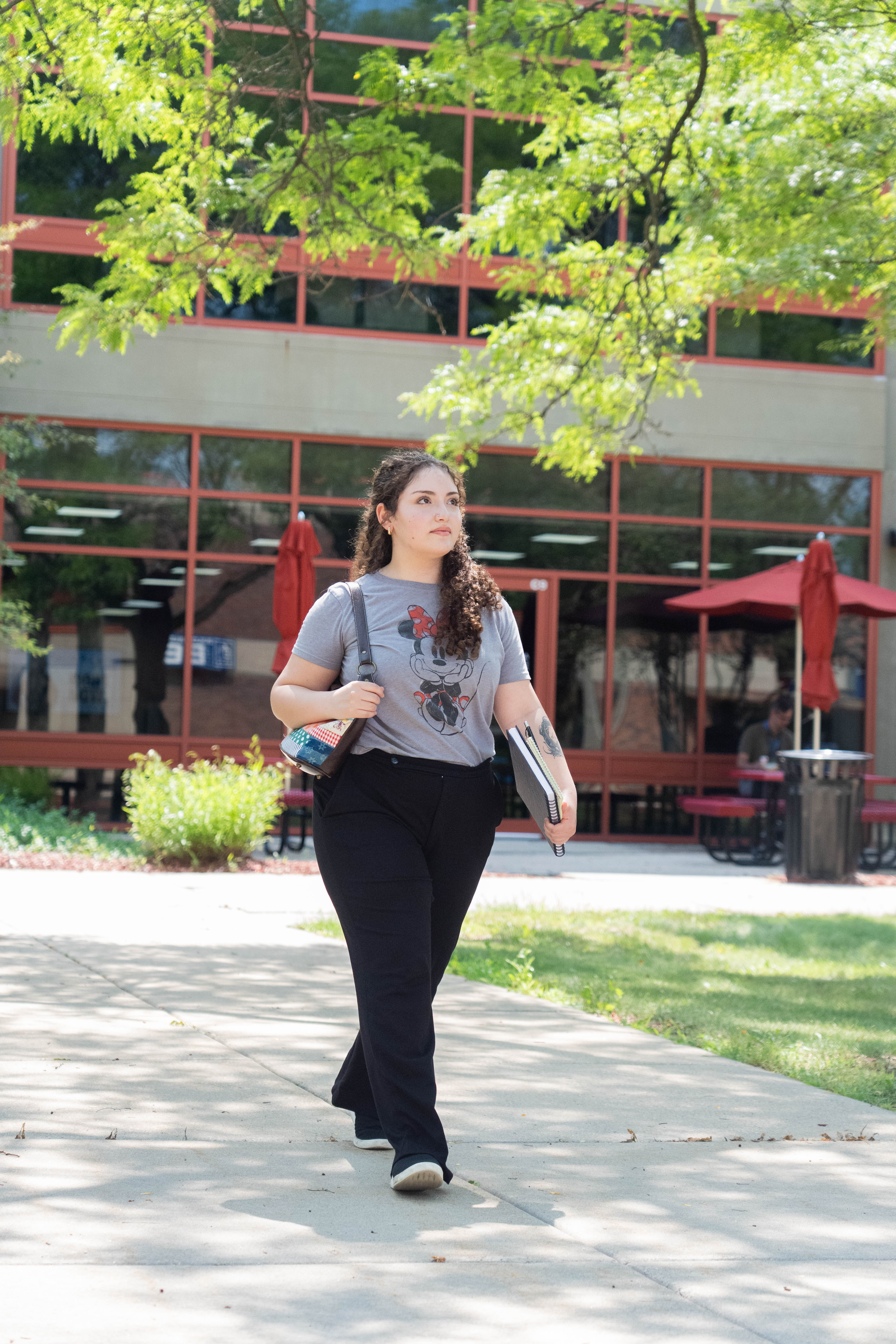 Female student walks through the courtyard in a gray shirt and black pants