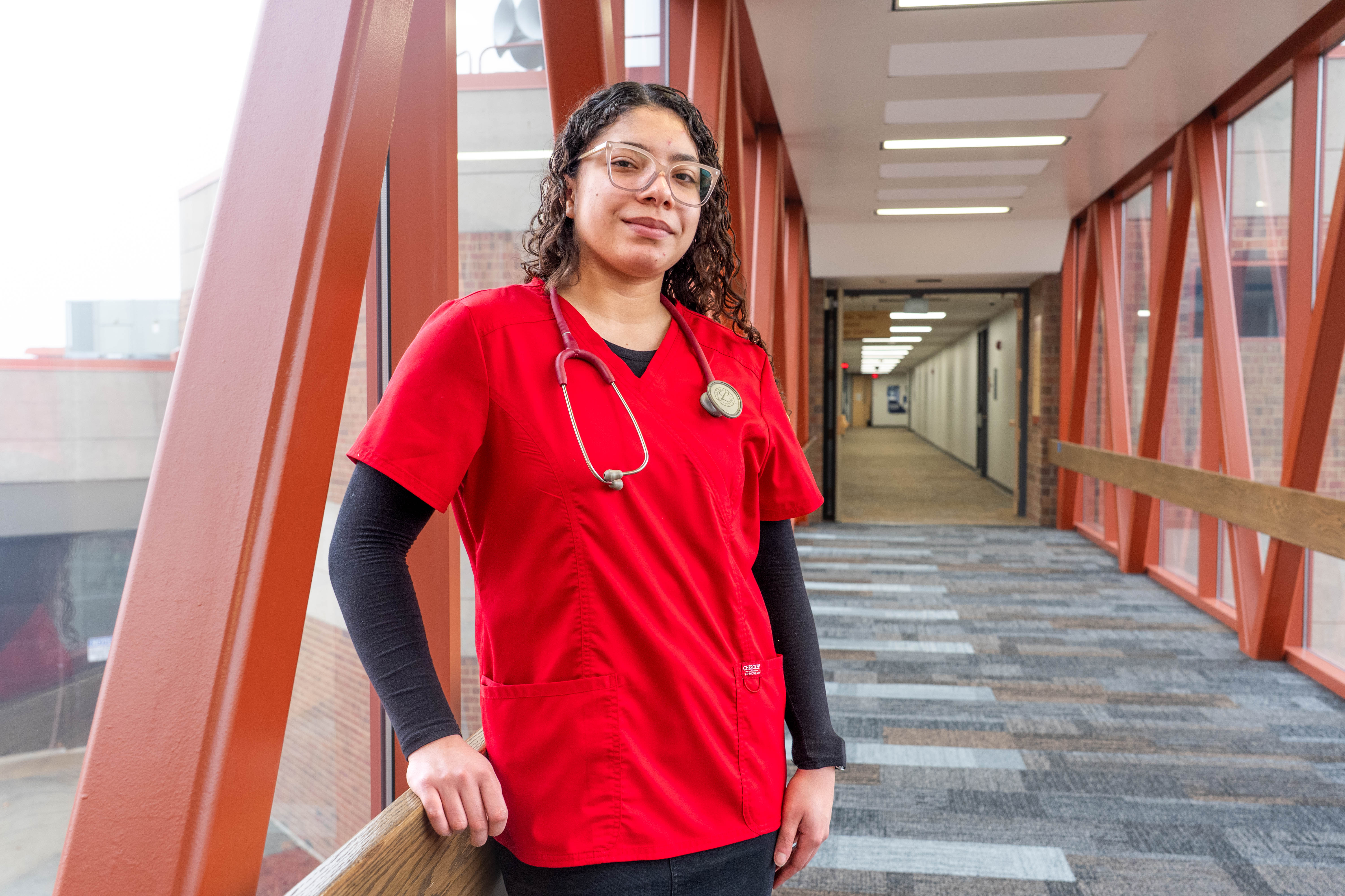 Yajaira Burgos in a red scrub top with stethoscope draped over her shoulders