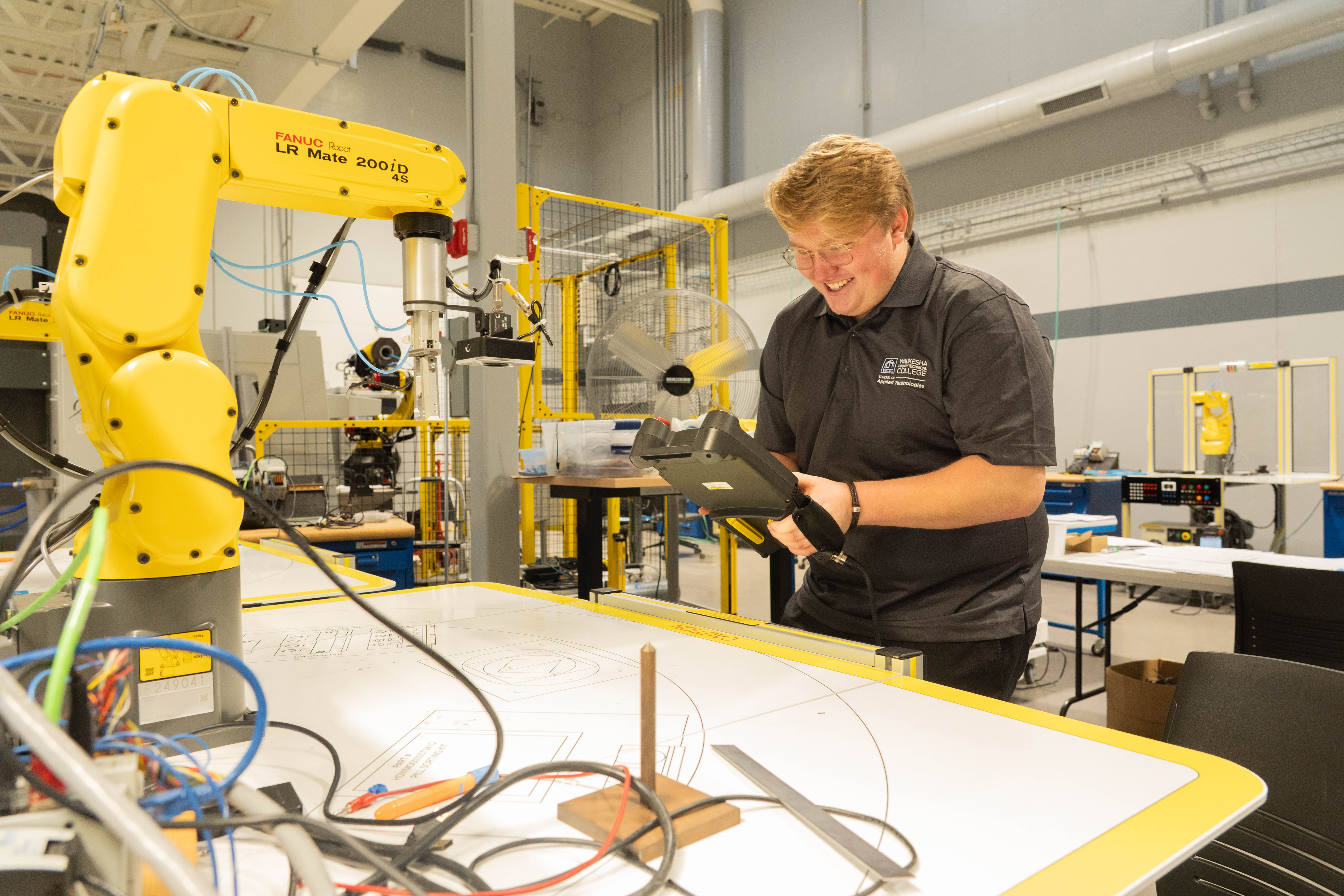 A student works on a pad that controls a robotic arm
