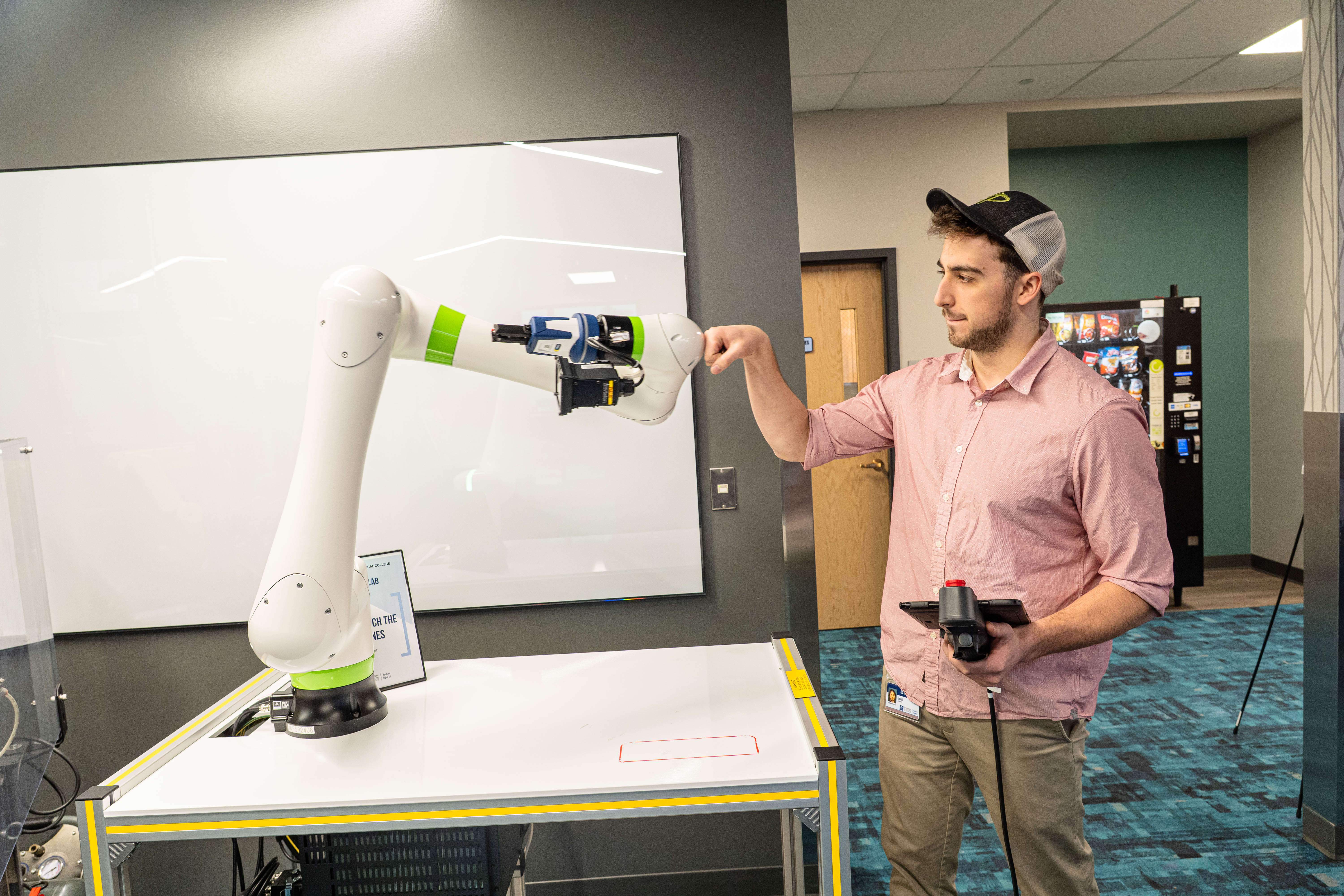 AI Fellow Joel Roberts gives a robotic arm a fist bump during a demonstration at the WCTC Spring 2026 Open House