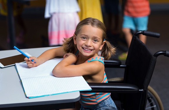 Young student in wheelchair writing in notebook