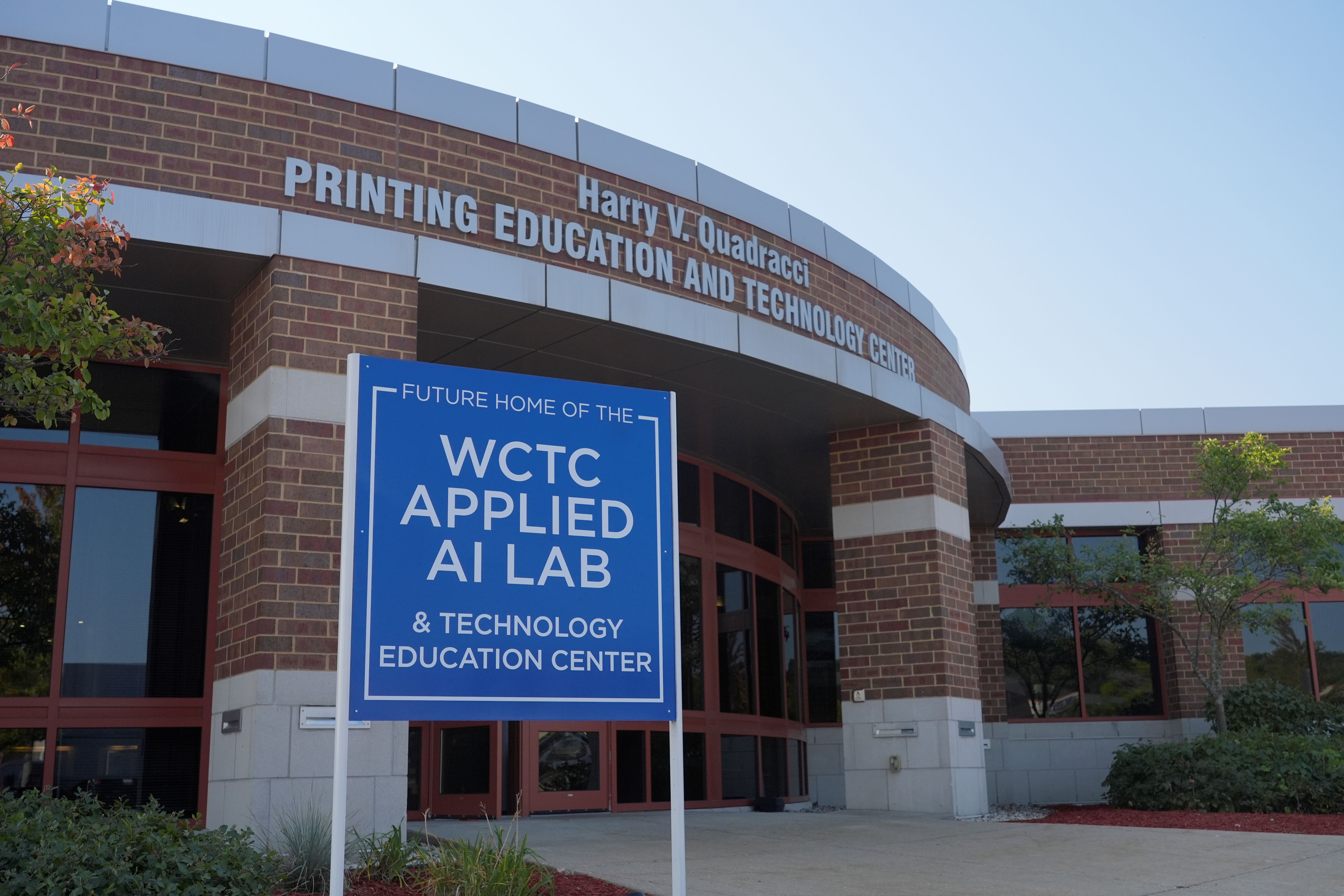 external photo of brown brick Building Q, with sign out front that says Applied AI Lab