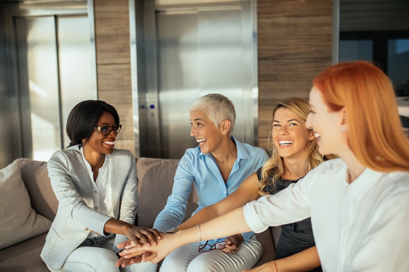 Group of four women in business attire smiling