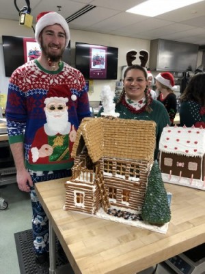 Students posing with decorated gingerbread houses