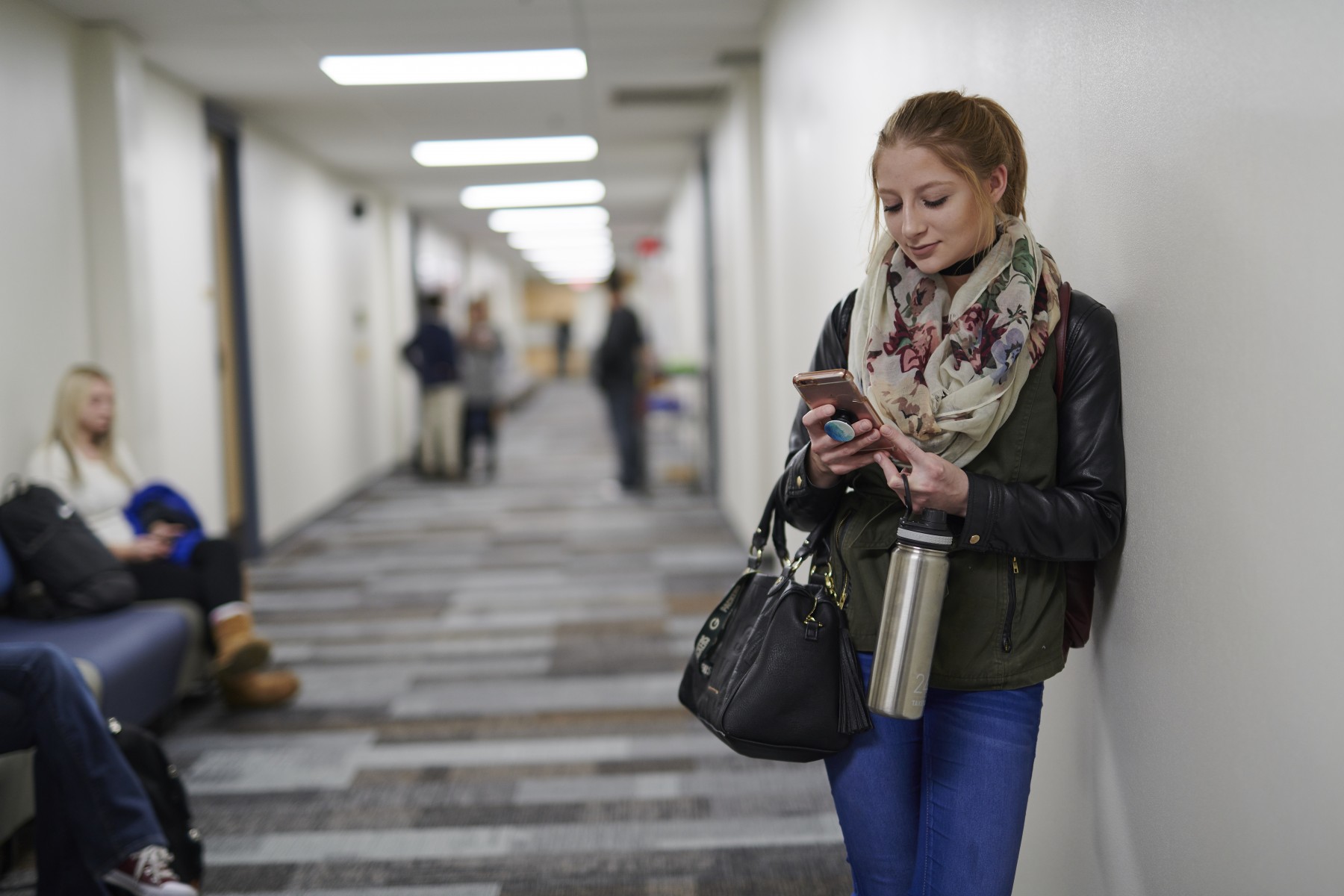 Student leaning on wall in campus hallway